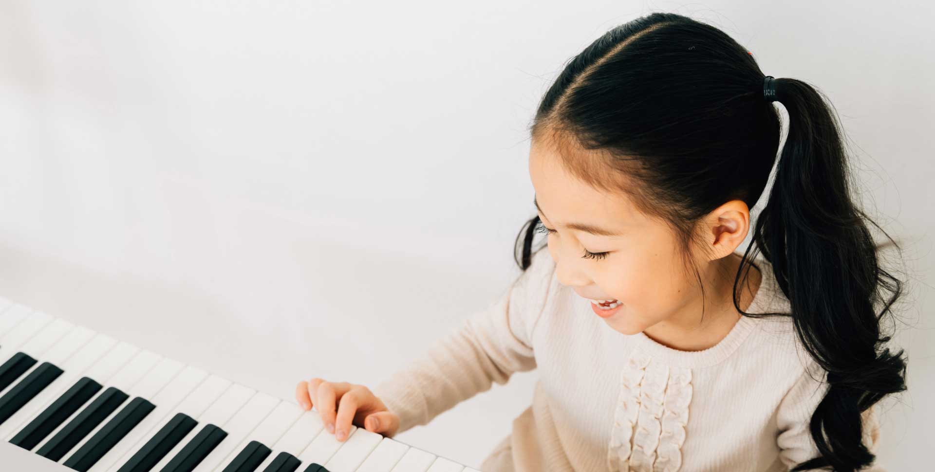 Young girl joyfully learning to play the piano at Da Capo Music Academy